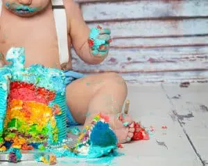 Cake Smash Photography East Grinstead West Sussex The hands and feet of a rainbow icing covered child at a cake smash photo shoot