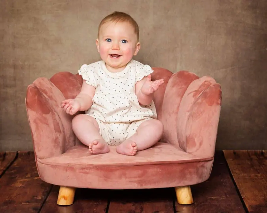 Baby Photography East Grinstead West Sussex a baby sits in a pink chair against a fine art brown canvas backdrop