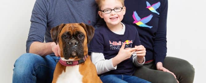 a family poses with two boys and a boxer dog