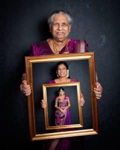 Three generations in a family photographed holding a picture frame which contains an image of the next generation down