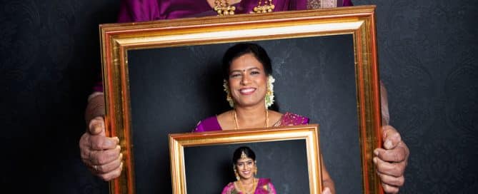 Three generations in a family photographed holding a picture frame which contains an image of the next generation down