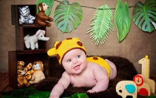 a little boy in a giraffe costume with jungle props