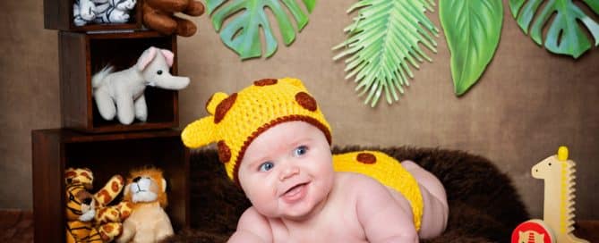 a little boy in a giraffe costume with jungle props
