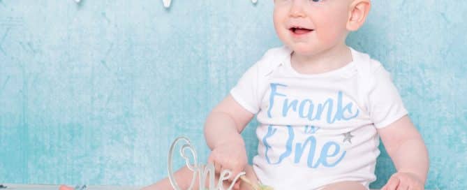 a little boy in a personalised tshirt sits behind his cake at his birthday photo shoot