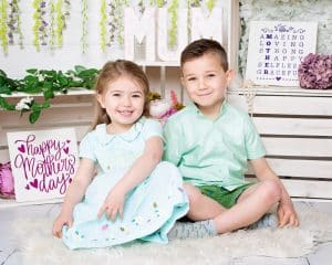 a little boy and girl pose in a mother's day themed set