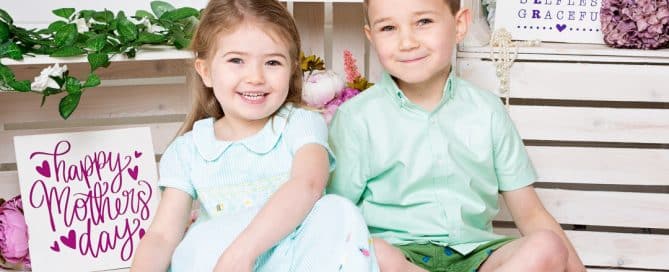 a little boy and girl pose in a mother's day themed set
