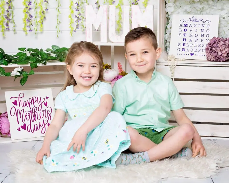 a little boy and girl pose in a mother's day themed set