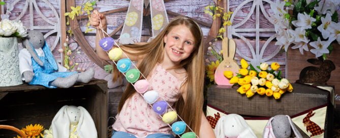 a little girl posted with a happy easter sign at a bunny themed easter photo shoot set