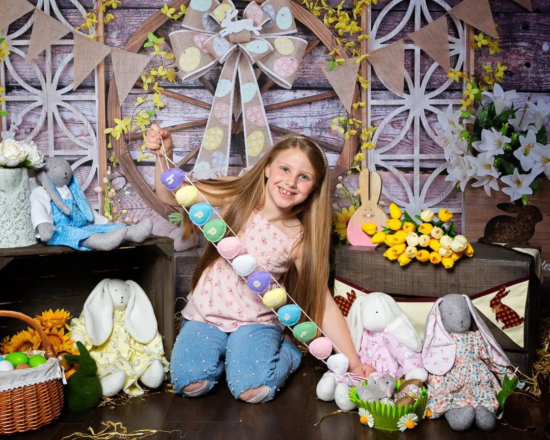 Easter Photo Shoots West Sussex 2022 a little girl posted with a happy easter sign at a bunny themed easter photo shoot set