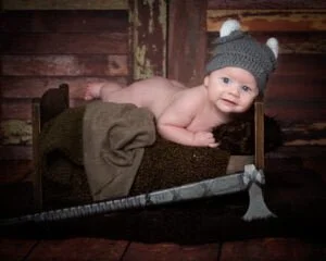 a baby on a bed dressed as a Viking at a themed photo shoot