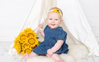 a little girl poses with sunflowers and a matching headband