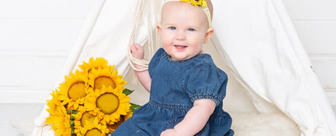 a little girl poses with sunflowers and a matching headband