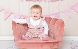 A pink chair prop is featured in an image with a smiling baby girl