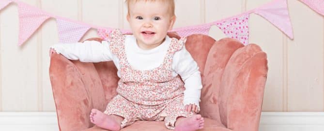 A pink chair prop is featured in an image with a smiling baby girl