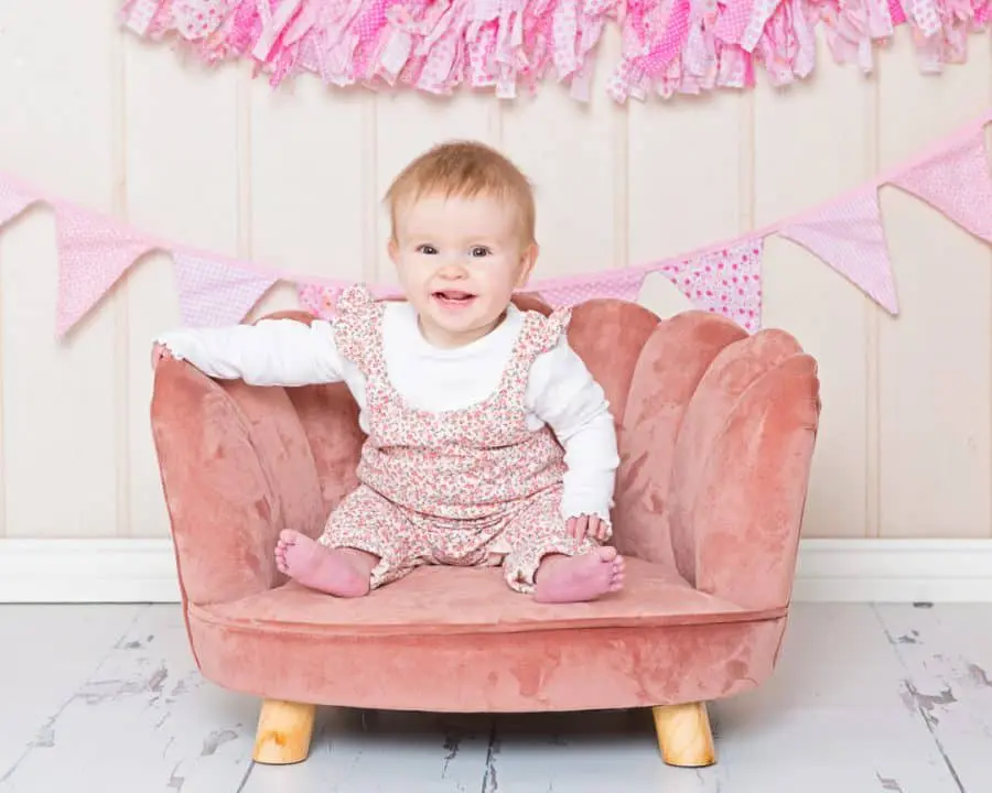 A pink chair prop is featured in an image with a smiling baby girl