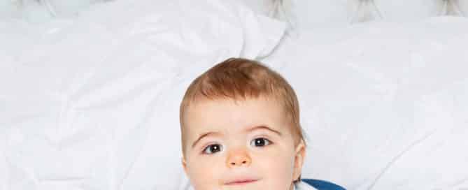 a baby on his tummy on a white bed set in my studio