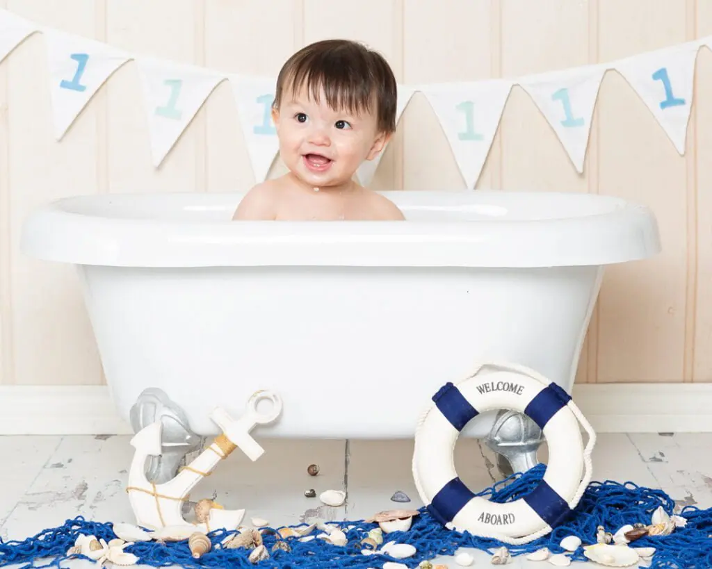 a little boy sits in a bathtub surrounded by nautical themed accessories