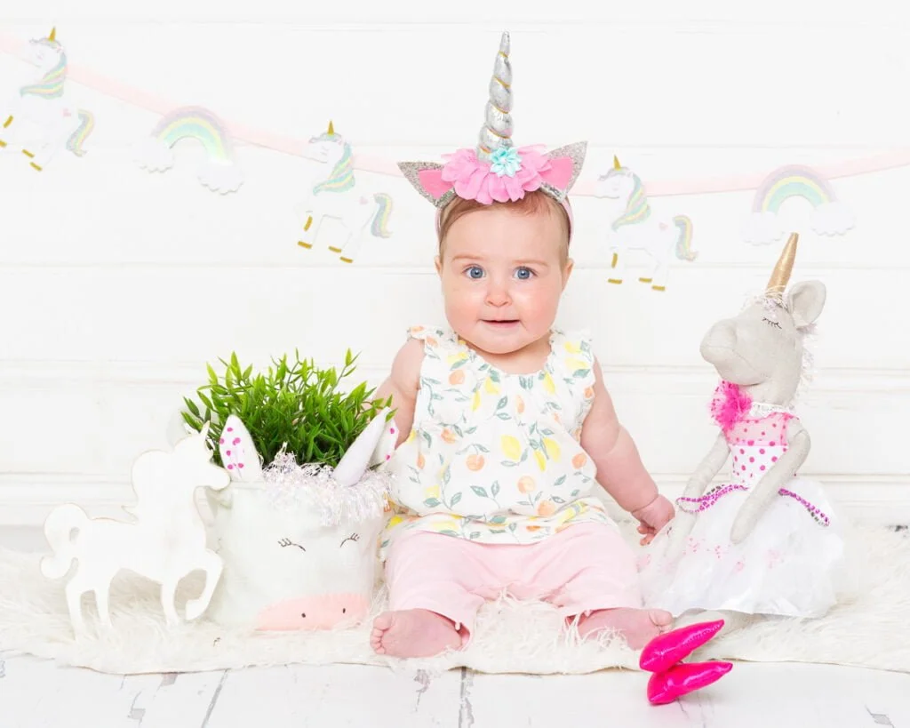 a little girl in a unicorn dress and headband with unicorn magical props