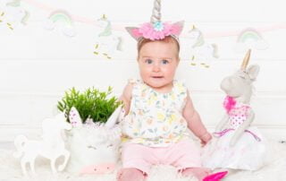 a little girl in a unicorn dress and headband with unicorn magical props