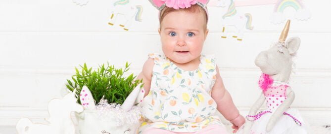 a little girl in a unicorn dress and headband with unicorn magical props