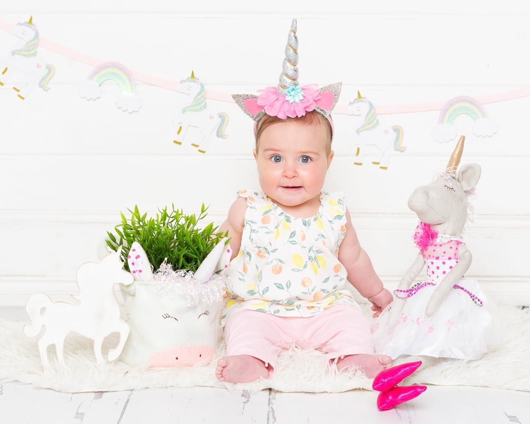 a little girl in a unicorn dress and headband with unicorn magical props