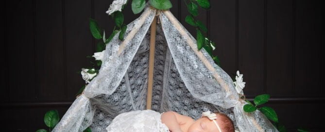 a lace wrapped newborn in a lace prop tent