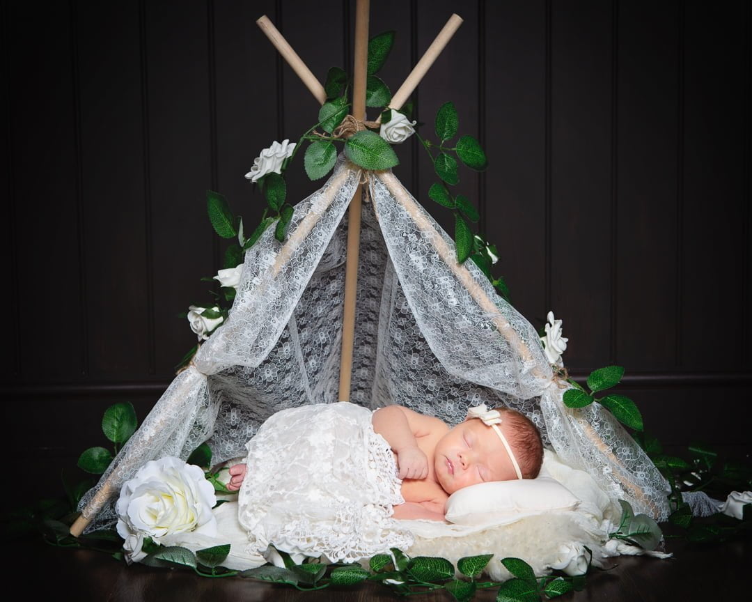 a lace wrapped newborn in a lace prop tent