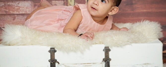 a little girl in a peach outfit on my vintage suitcase prop