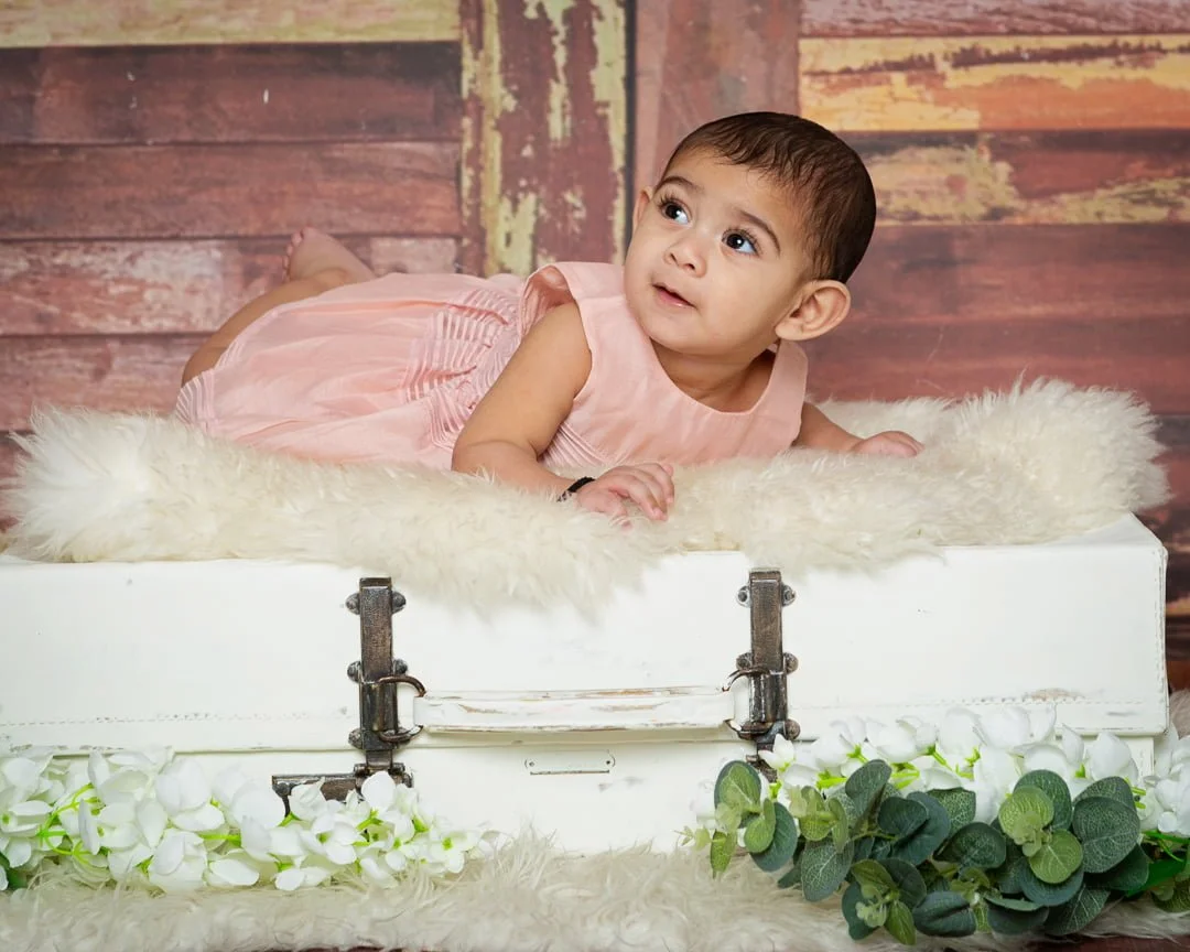 a little girl in a peach outfit on my vintage suitcase prop