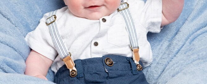 a little boy waves at the camera on blue blanket