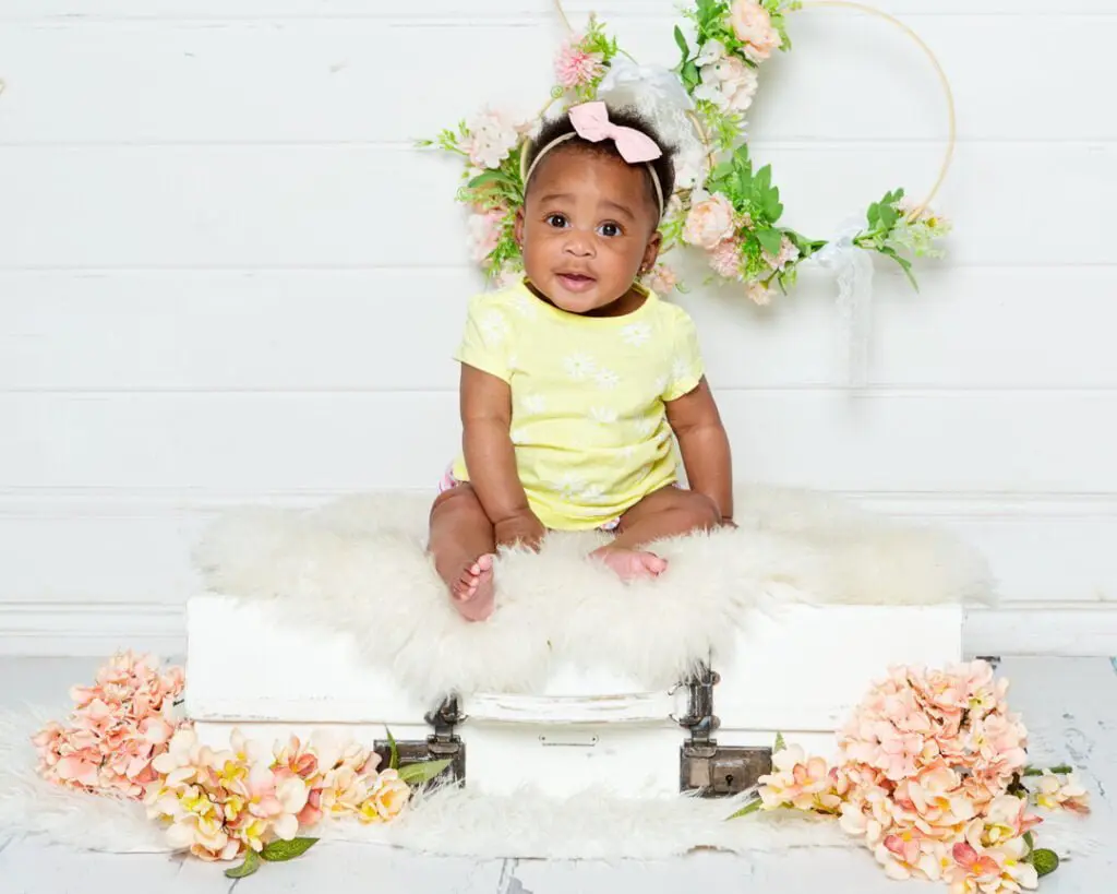 a little girl in a yellow outfit sits on my vintage suitcase