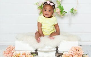 a little girl in a yellow outfit sits on my vintage suitcase