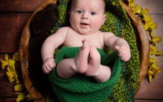 a baby in a wood bowl with daffodils