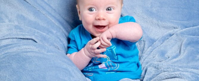 a little boy plays with his hands on a blue blanket