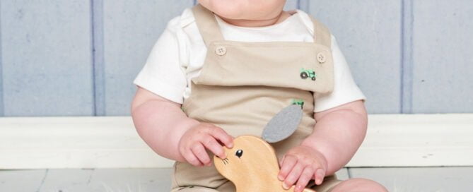 a little boy and a wooden toy against a blue backdrop