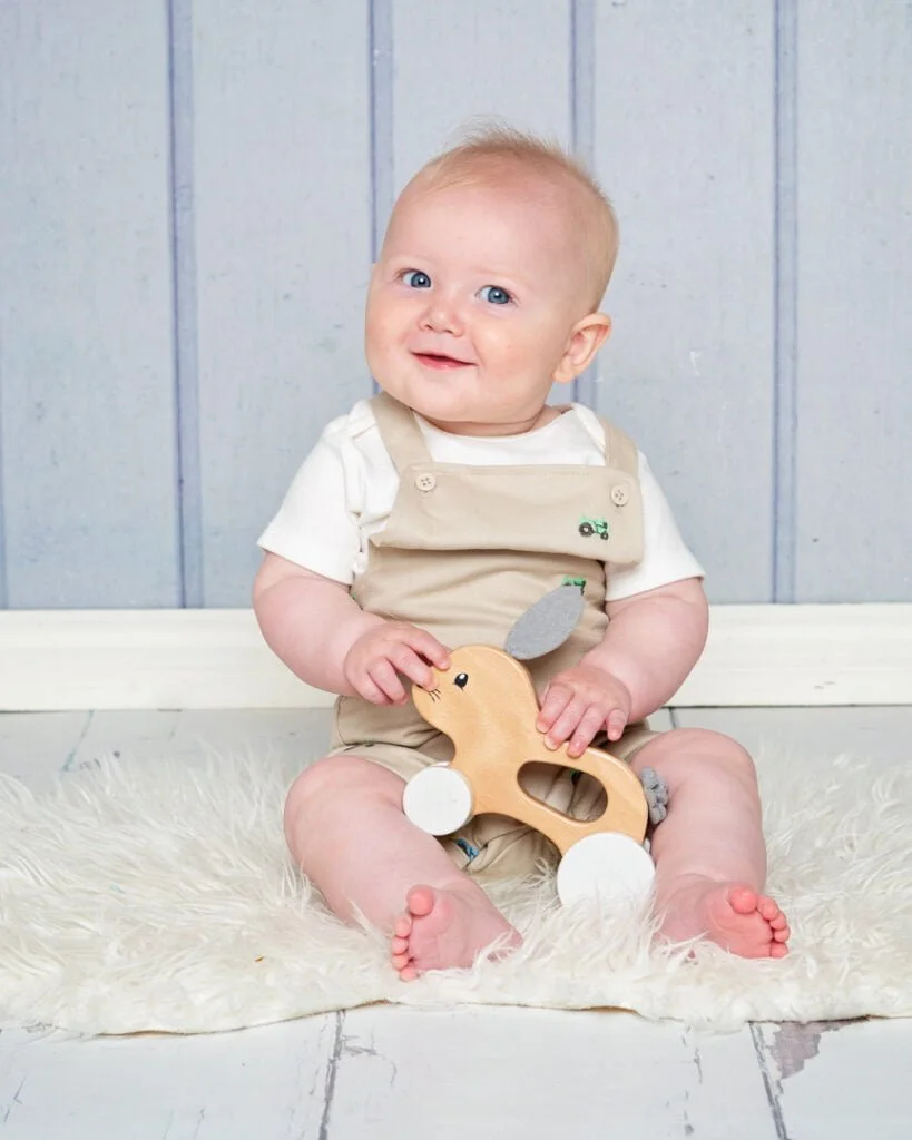 Baby Photography East Grinstead West Sussex a little boy and a wooden toy against a blue backdrop