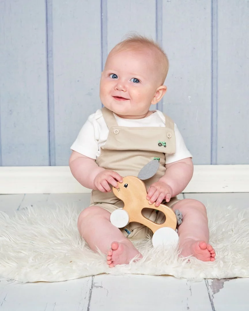 a little boy and a wooden toy against a blue backdrop