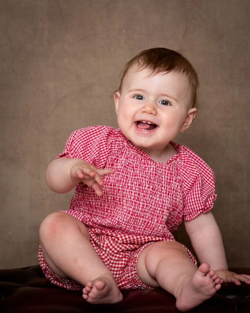 a girl in a red gingham outfit against a fine art backdrop