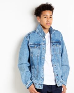A young man poses in a denim jacket for a professional photo