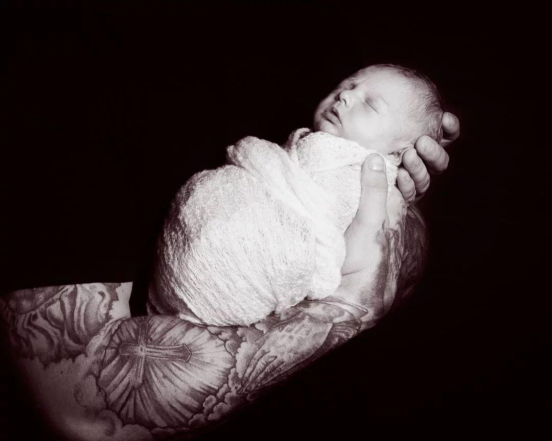 Newborn Photography East Grinstead West Sussex a black and white image of a newborn sleeping in his dads arms
