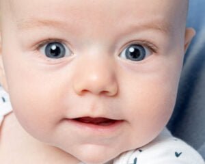 a close up of a wide eyed baby in the studio