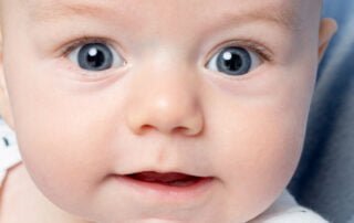 a close up of a wide eyed baby in the studio