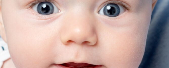 a close up of a wide eyed baby in the studio