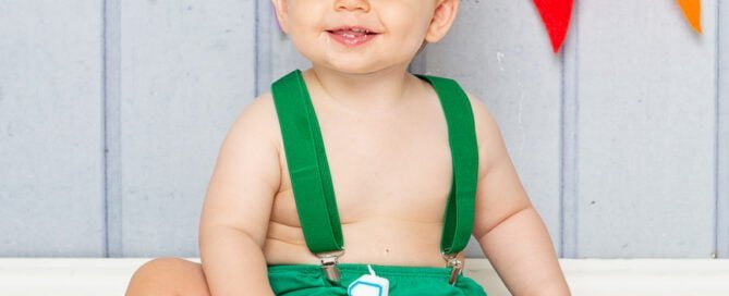 a little boy in a green and gold outfit eating a birthday cake