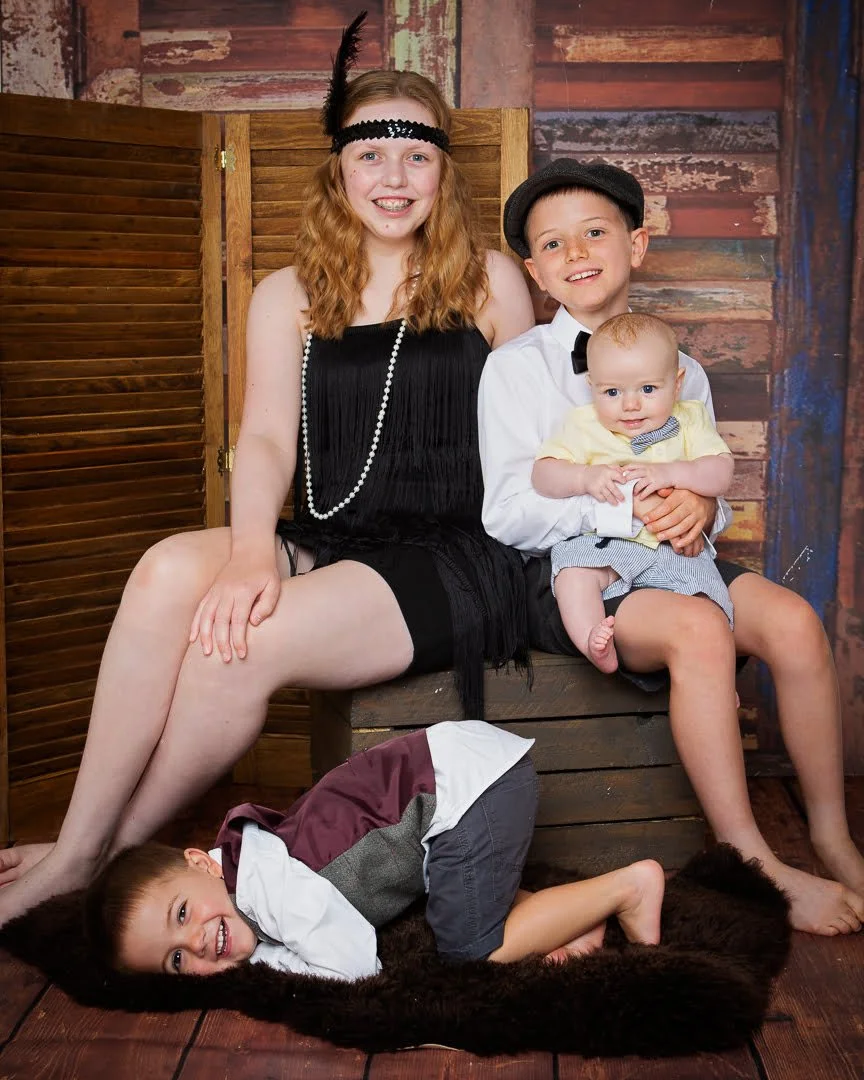 A family of four children poses dressed in 1920s outfits