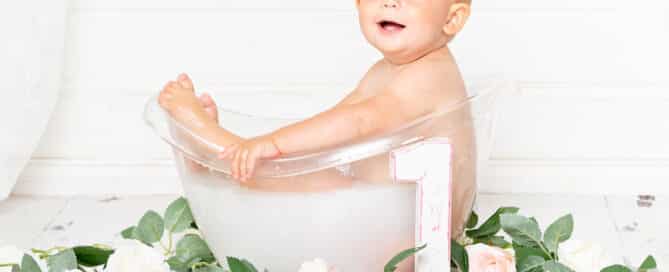 a little girl in a milk bath with flowers at a first birthday photo shoot