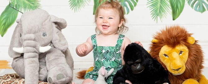a litle girl in a jungle themed outfit poses with a collection of jungle toys