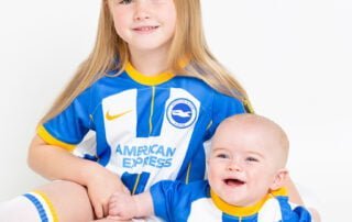 Two siblings pose in matching Brighton Football shirts