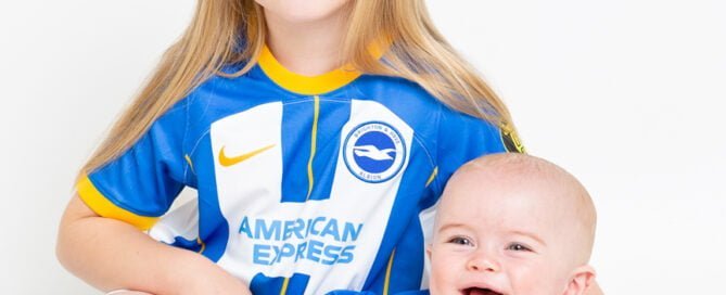 Two siblings pose in matching Brighton Football shirts