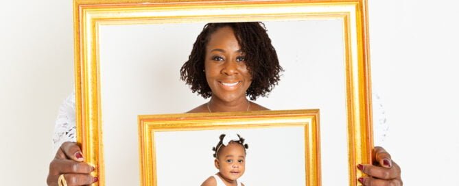 three generations of family pose for a family photo, each holding a frame with a picture of the generation down